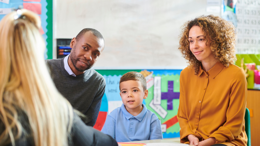 A mom, dad, child, and teacher are sitting at a table discussing the child's education as a Highly Sensitive child.